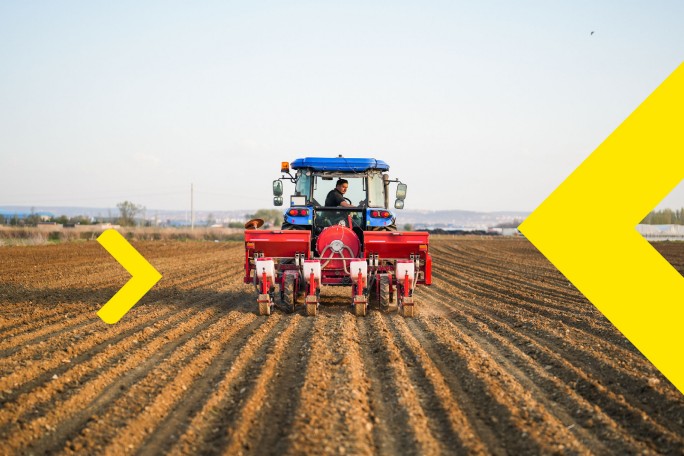 Traktor na obrađenom polju koji predstavlja korišćenje kredita za obrtna sredstva banke u poljoprivredi