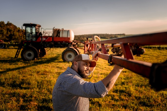 Poljoprivrednik priprema mašinu za prskanje na njivi, siguran da mu pozajmica po tekućem računu obezbedjuje neophodna obrtna sredstva