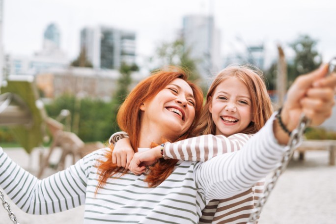A happy mother and daughter on a swing representing financial peace of mind through loan repayment relief options