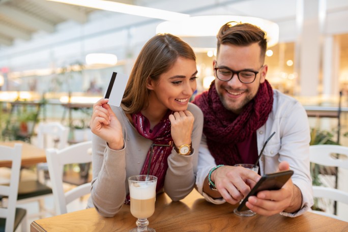 Nasmejani par koristi pametni telefon i platnu karticu za brzu e-commerce kupovinu u restoranu