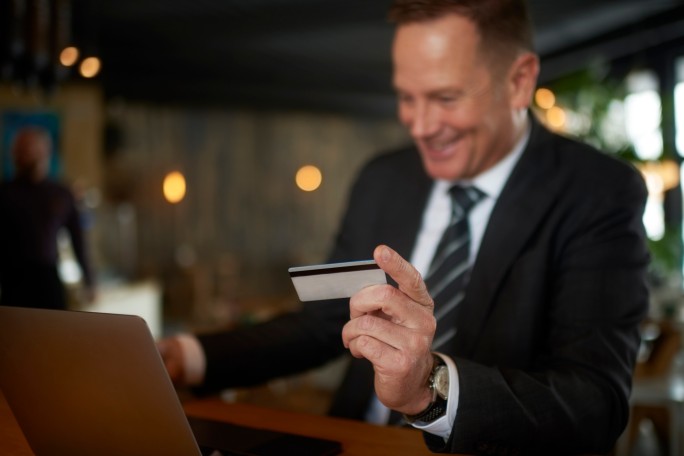 Nasmejani poslovni čovek koristi premium debitnu karticu za sigurno online plaćanje i uživanje u ekskluzivnim bankarskim pogodnostima