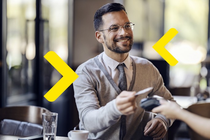 Nasmejani poslovni čovek koristi premium karticu za plaćanje računa u restoranu uz ekskluzivne pogodnosti