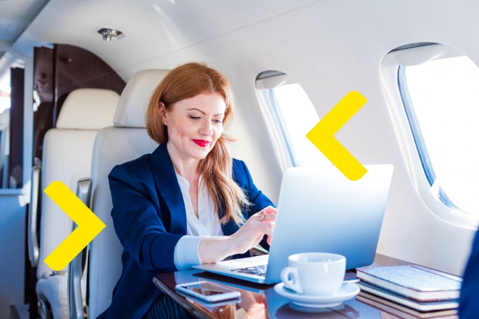 Poslovna žena koristi digitalne bankarske usluge u privatnom avionu uz privilegije koje pruža Visa Infinite kartica