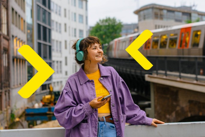 Devojka sluša muziku i koristi digitalne usluge Raiffeisen banke na svom mobilnom telefonu