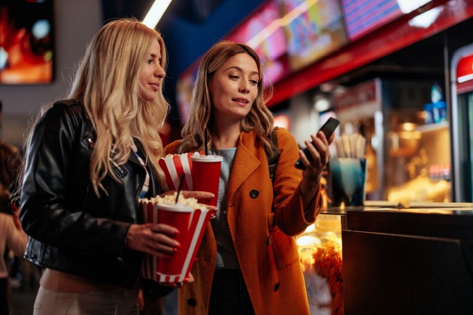 Žene u bioskopu spremaju se da plate ulaznice i hranu koristeći IPS plaćanje telefonom