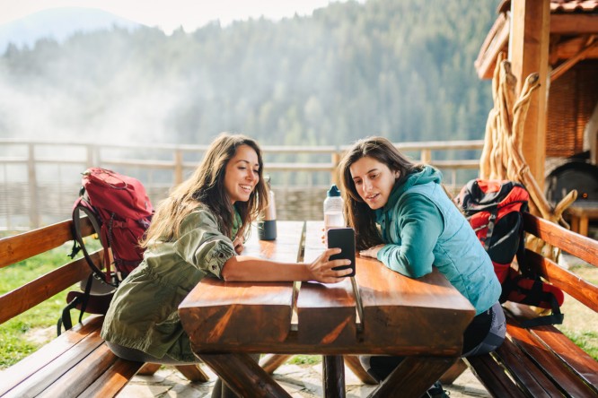 Two backpacker girls taking a photo of themselves in the mountain.