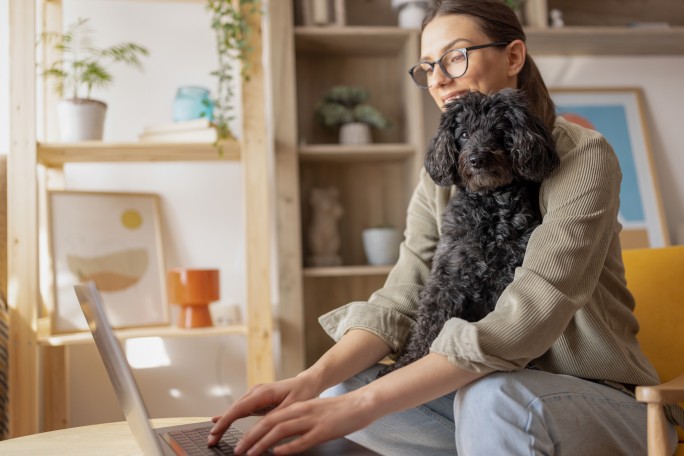 Žena sa kučetom iz svog stana preko laptopa pregleda iPortal Raiffeisen banke