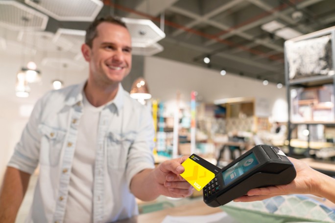 Čovek u prodavnici plaća karticom Raiffeisen banke