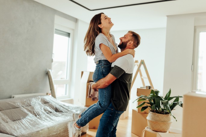 Mladi par zagrljen u novom stanu kupljenom uz pomoć stambenog kredita