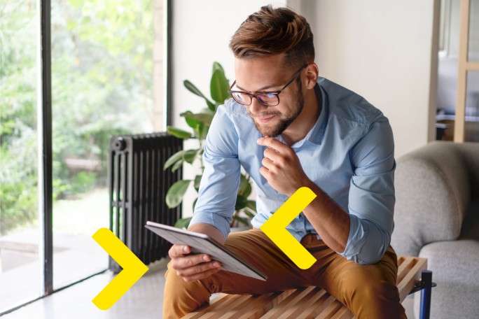 Mladi preduzetnik istražuje uslove za start up kredit na tabletu za pokretanje svog prvog biznisa