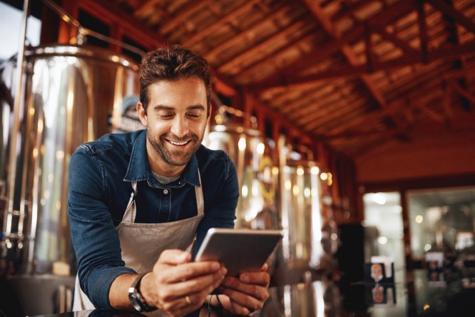 Mladi čovek u svom preduzeću na tabletu pregleda preduzetnik paket račun