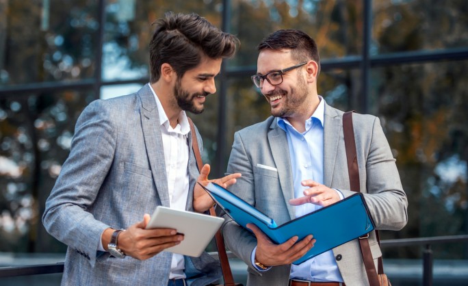 Dva mlada preduzetnika gledaju u svoje nove otvorene preduzetnik plus pakete